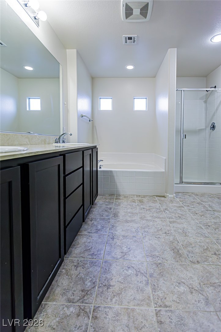 11009 Ketchikan Street Las Vegas, NV 89179 - Photo 45 of 59 Bathroom featuring double vanity, a garden tub, a stall shower, and recessed lighting