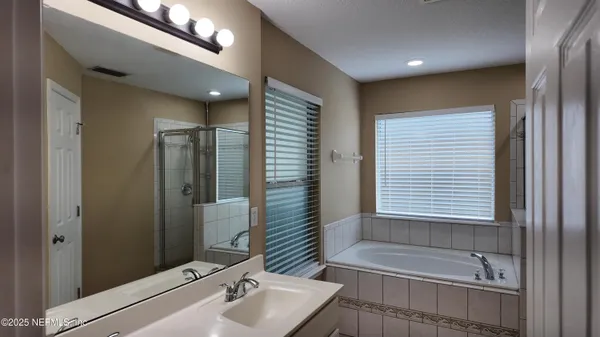 a bathroom with a tub sink and mirror