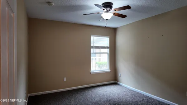 an empty room with a window and a fan