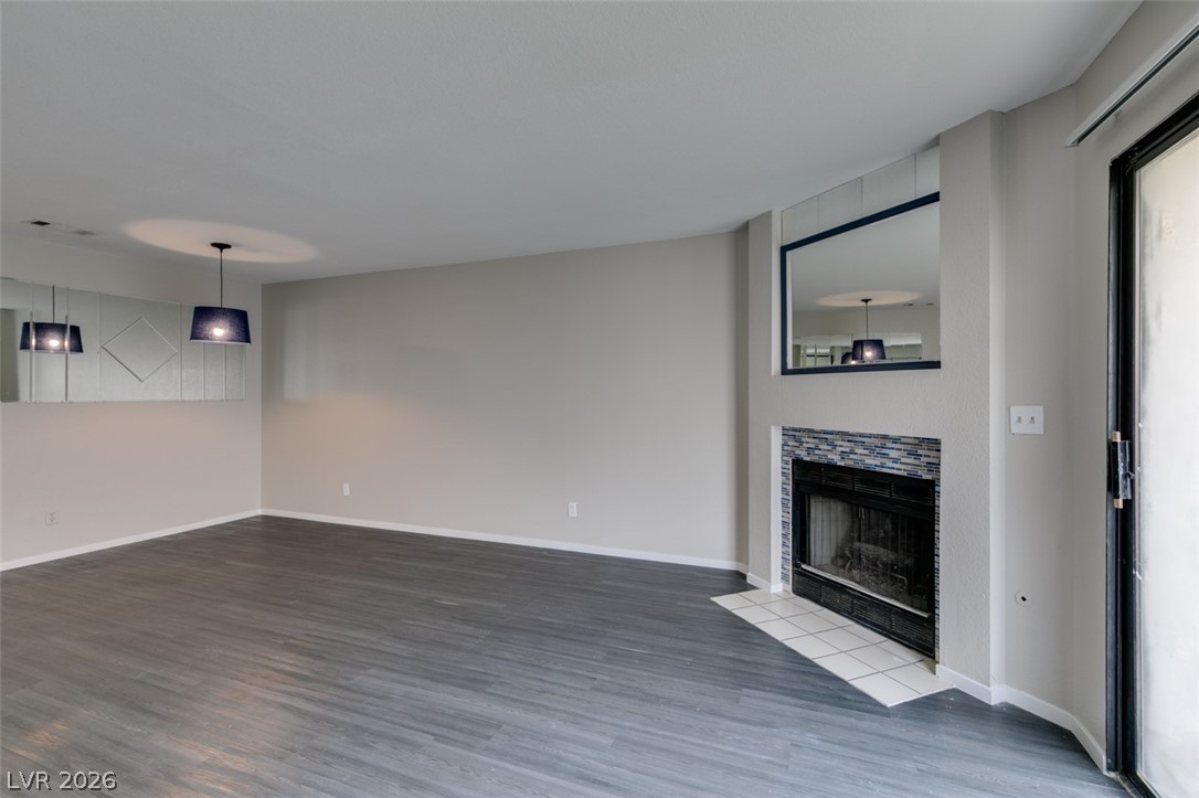 810 North Sloan Lane, Unit 103 Las Vegas, NV 89110 - Photo 4 of 16 Unfurnished living room featuring wood finished floors, a tile fireplace, and baseboards