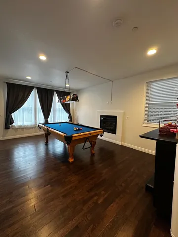 a living room with pool table and a wooden floor