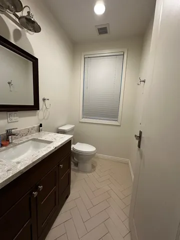 a bathroom with a granite countertop sink toilet and mirror