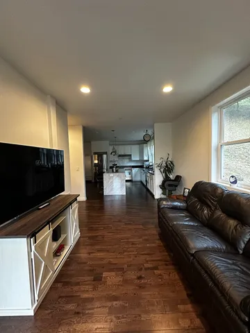 a kitchen with stainless steel appliances kitchen island granite countertop a stove a refrigerator a sink and a dining table with wooden floor