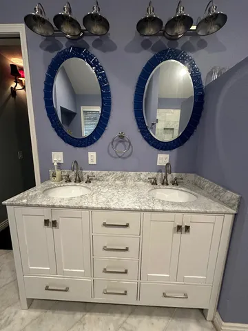 a bathroom with a granite countertop double vanity sink and a mirror