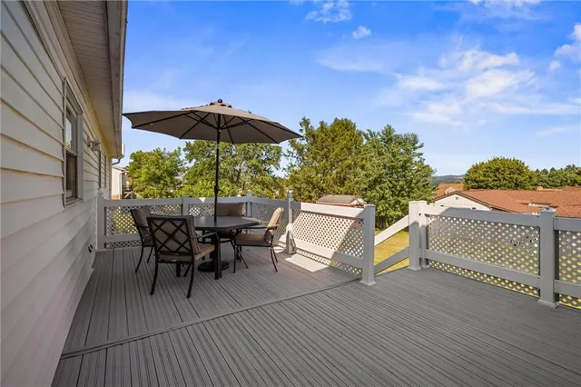 a view of a roof deck with table and chairs under an umbrella with wooden floor
