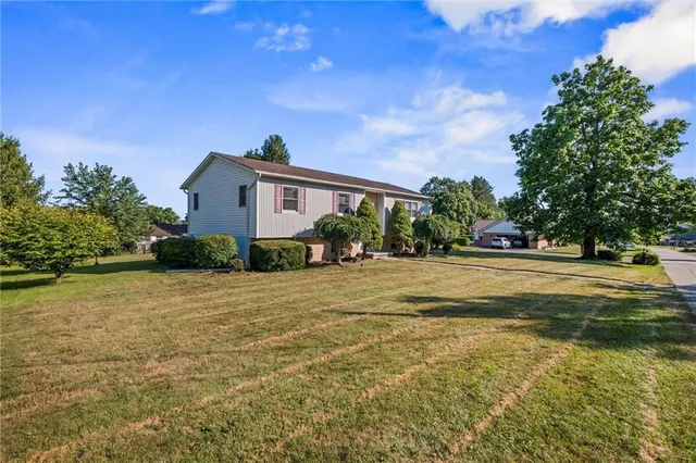 a front view of a house with a yard and trees