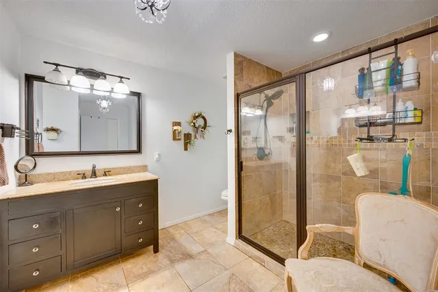 a bathroom with a granite countertop sink a mirror and shower