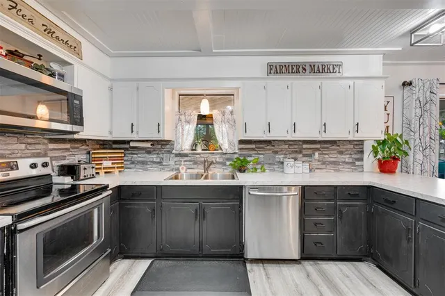 a kitchen with granite countertop a stove a sink dishwasher and a refrigerator with wooden floor