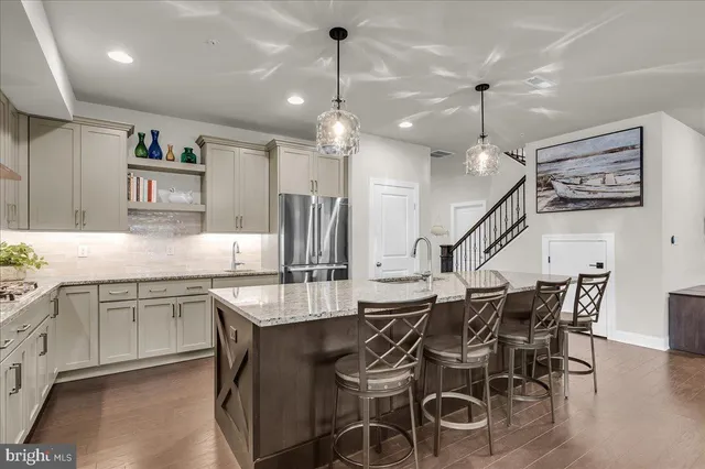 a kitchen with stainless steel appliances kitchen island granite countertop a dining table chairs and white cabinets