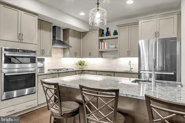 a kitchen with kitchen island granite countertop a table chairs stove and cabinets