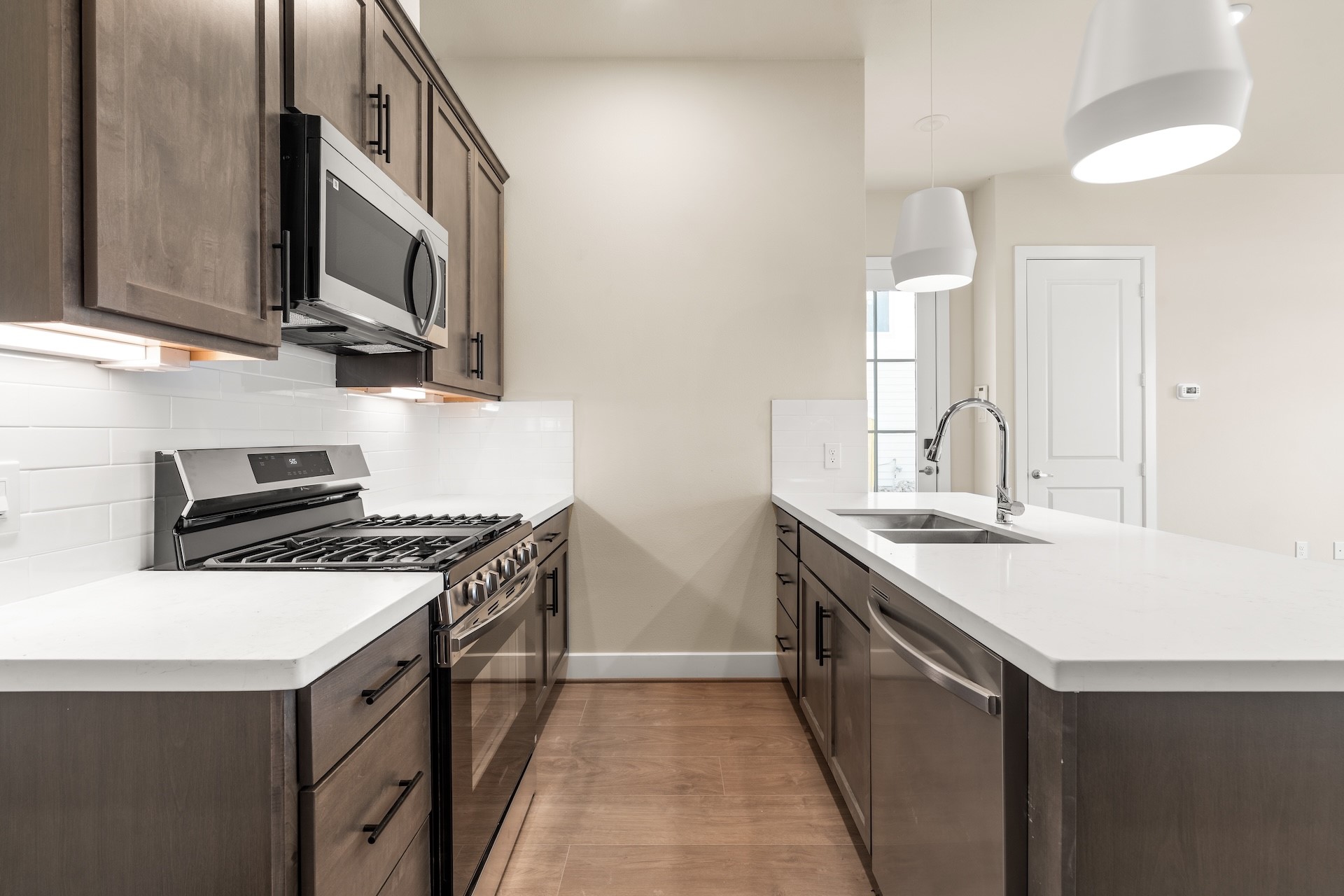 6521 Rena Street Houston, TX 77092 - Photo 5 of 24 Chef's workspace detail — gas cooktop with stainless microwave vent hood, crisp white tile backsplash, under-cabinet lighting, and quartz island prep space.