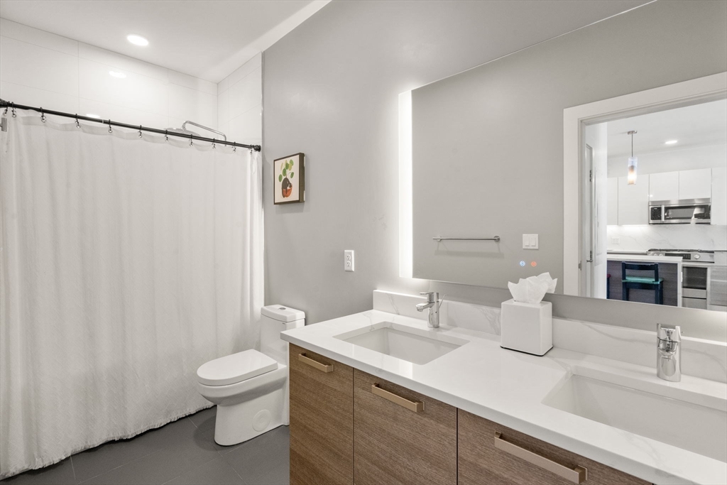 30 Penniman Road, Unit 506 Boston, MA 02134 - Photo 17 of 25 a bathroom with a granite countertop sink mirror vanity and toilet