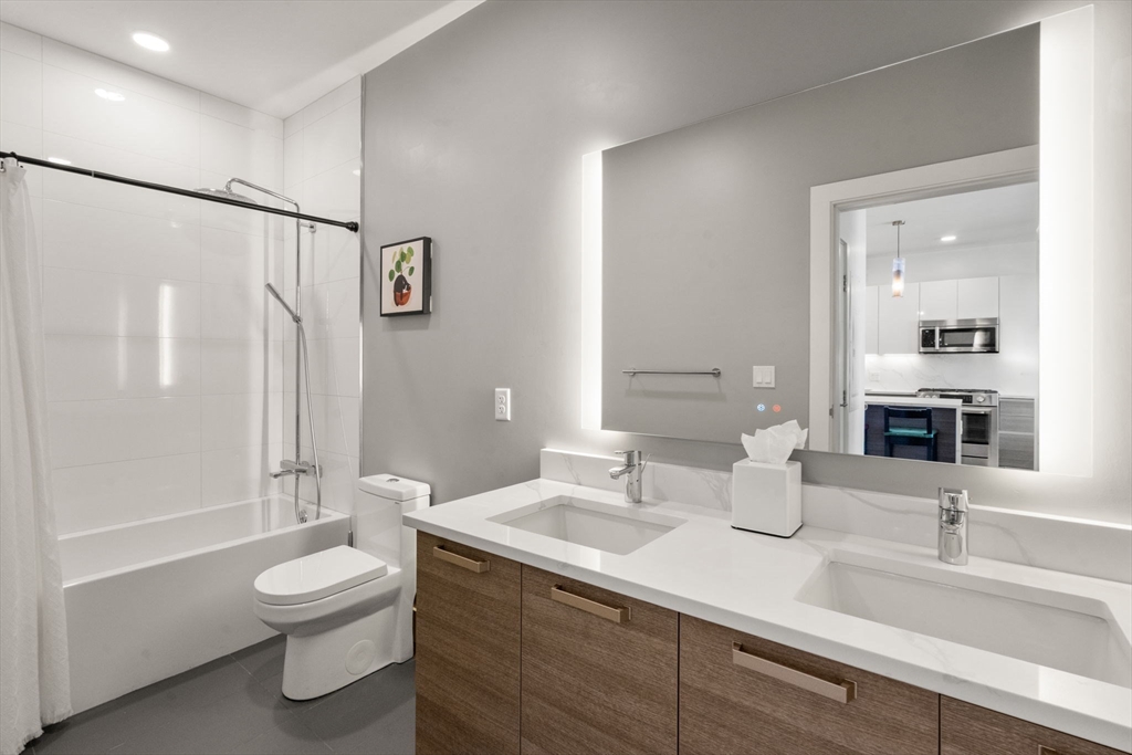 30 Penniman Road, Unit 506 Boston, MA 02134 - Photo 18 of 25 a bathroom with a double vanity sink toilet mirror and bathtub