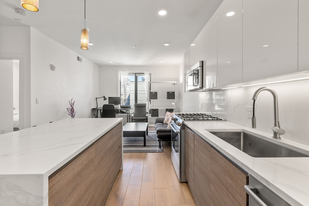 30 Penniman Road, Unit 506 Boston, MA 02134 - Photo 6 of 25 a large kitchen with stainless steel appliances a large counter top a stove and a sink