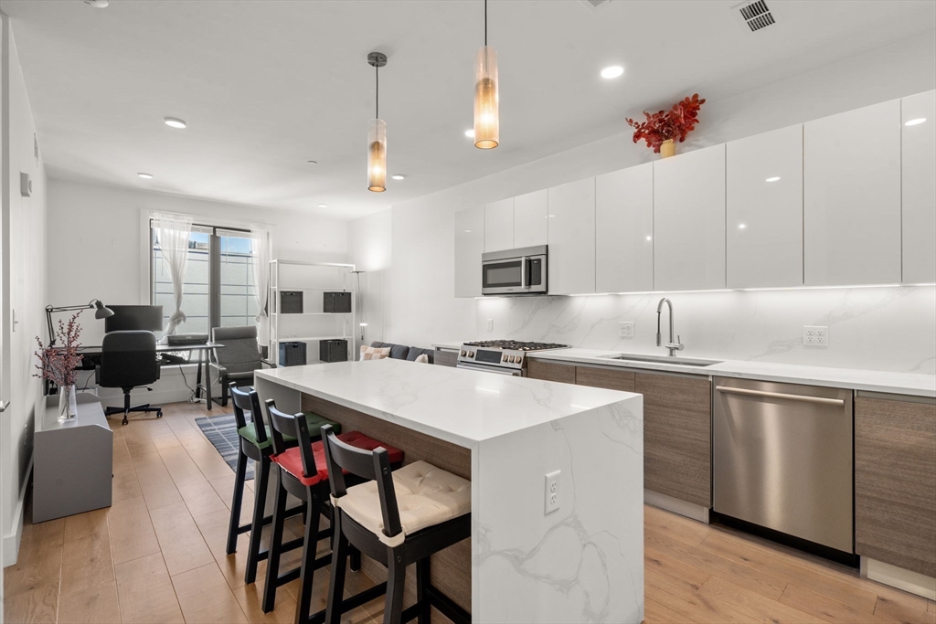 30 Penniman Road, Unit 506 Boston, MA 02134 - Photo 7 of 25 a kitchen with a stove a sink a dining table and chairs
