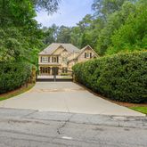 a view of a large house with large trees and plants