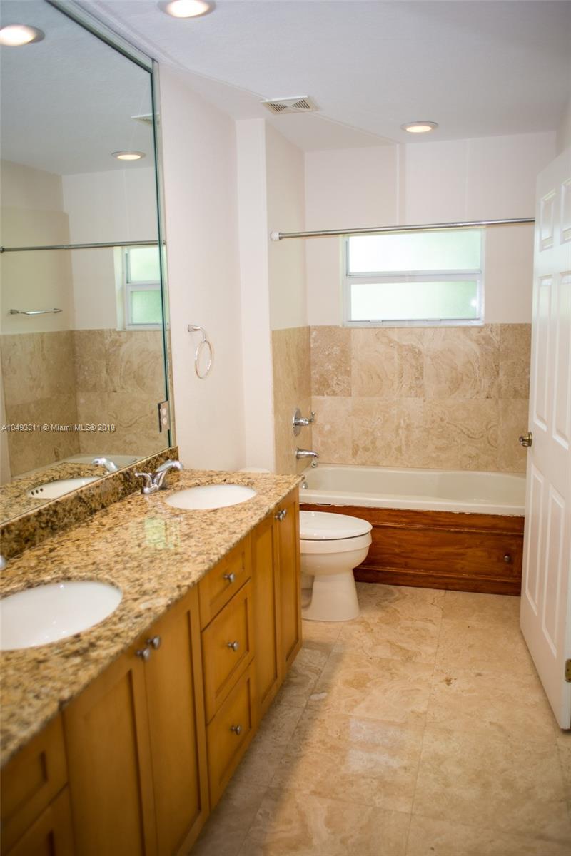 2980 Virginia Street, Unit 2980 Miami, FL 33133 - Photo 12 of 17 a bathroom with a granite countertop sink a toilet a mirror and bathtub