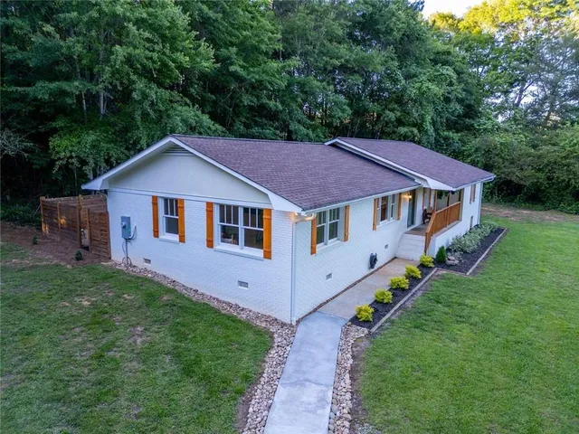 a backyard of a house with lawn chairs plants and tree