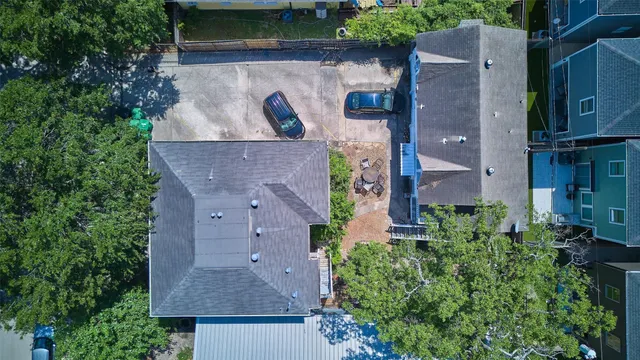 an aerial view of a house with yard and trees in the background