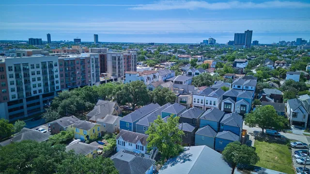 an aerial view of a city with lots of residential buildings ocean and mountain view in back