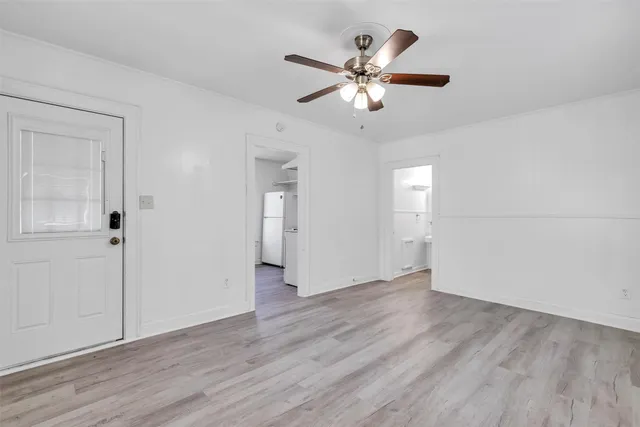an empty room with wooden floor closet and windows