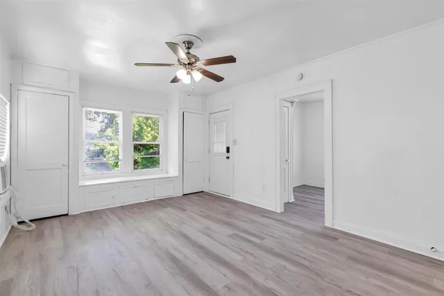 a view of empty room with wooden floor and fan