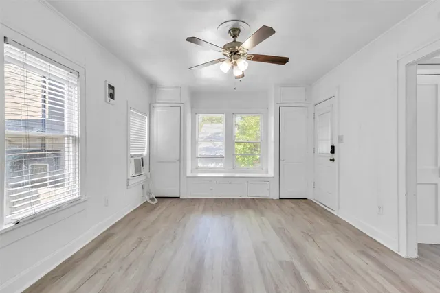 a view of an empty room with wooden floor and a window