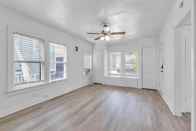 a view of an empty room with a window and wooden floor