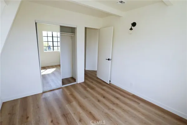 an empty room with wooden floor closet and windows