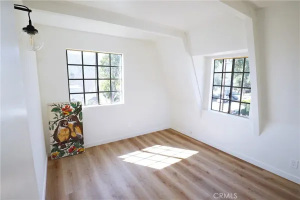 an empty room with wooden floor closet and windows