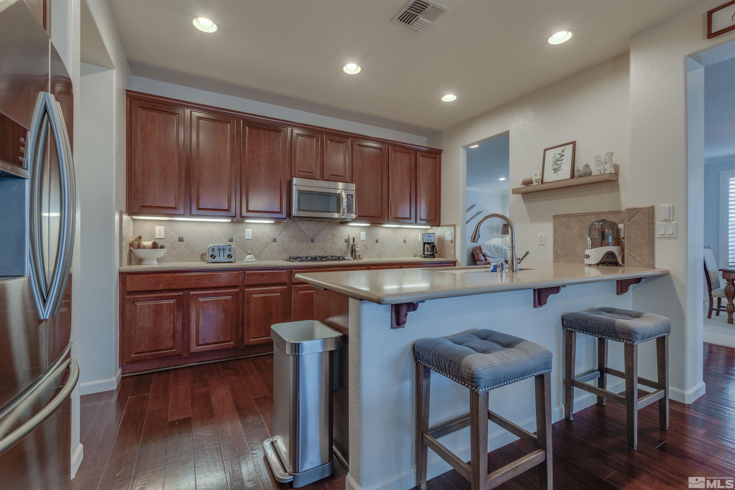 450 Haleb Court Reno, NV 89521 - Photo 8 of 31 a kitchen with kitchen island granite countertop wooden floors and wooden cabinets