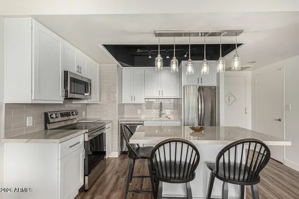 a kitchen with stainless steel appliances granite countertop a stove top oven a sink a dining table and chairs