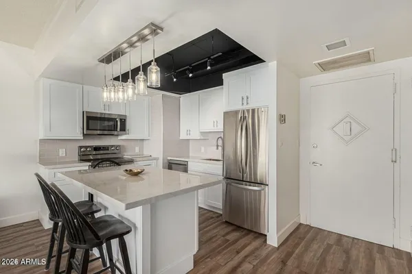 a kitchen with stainless steel appliances granite countertop a refrigerator a stove a sink dishwasher a dining table and chairs with wooden floor