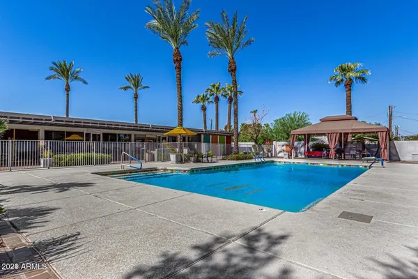 a view of a swimming pool with lawn chairs under an umbrella