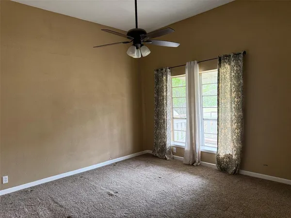 an empty room with windows and fan