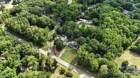 an aerial view of residential house with outdoor space and trees all around