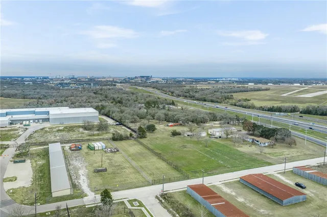 an aerial view of a residential houses with outdoor space and trees