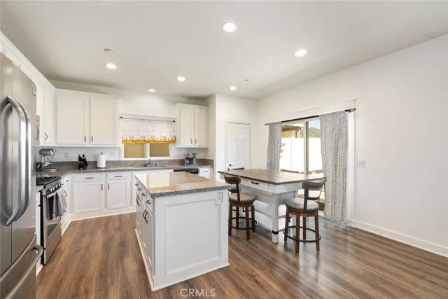 a kitchen with a refrigerator a stove a sink and a dining table with wooden floor