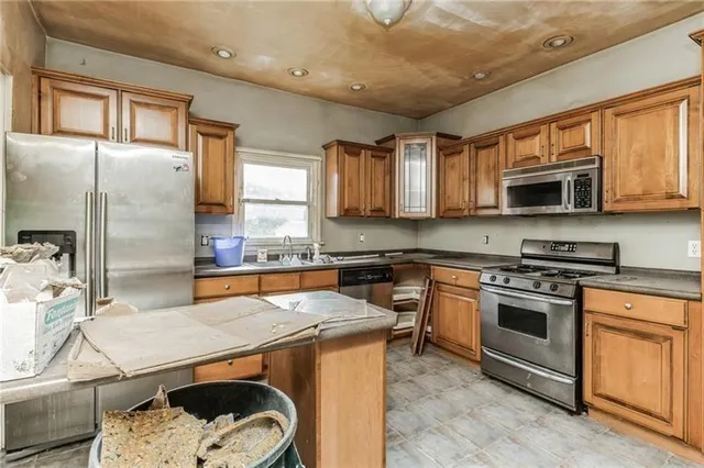 a kitchen with stainless steel appliances granite countertop a stove top oven a sink dishwasher a refrigerator and cabinets with wooden floor