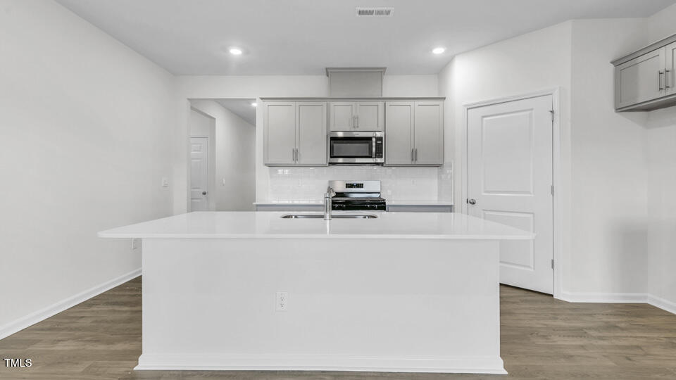 806 Comice Pear Way Willow Spring, NC 27592 - Photo 8 of 37 a kitchen with kitchen island a white counter top and refrigerator