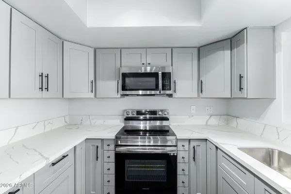 a kitchen with white cabinets and black appliances