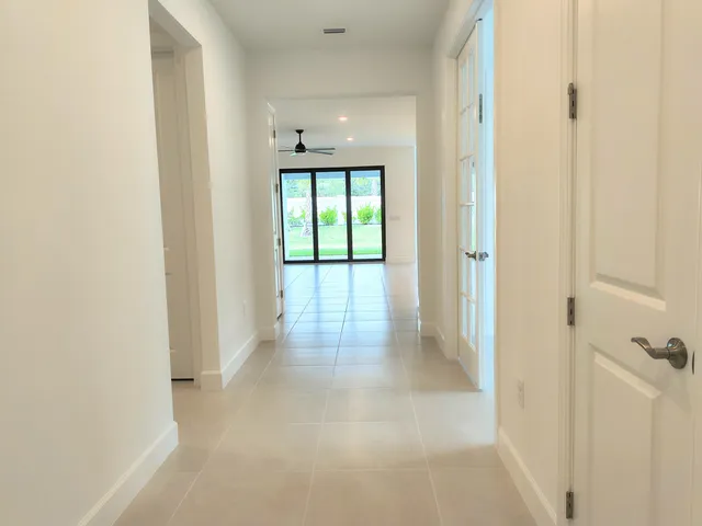 a view of a hallway with wooden floor and a bathroom