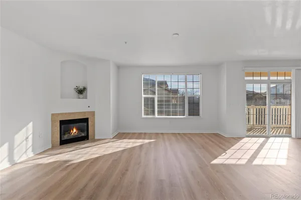 a view of an empty room with wooden floor fireplace and a window