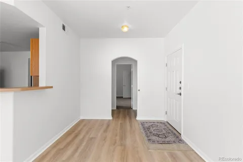 a view of a hallway with wooden floor and a bathroom