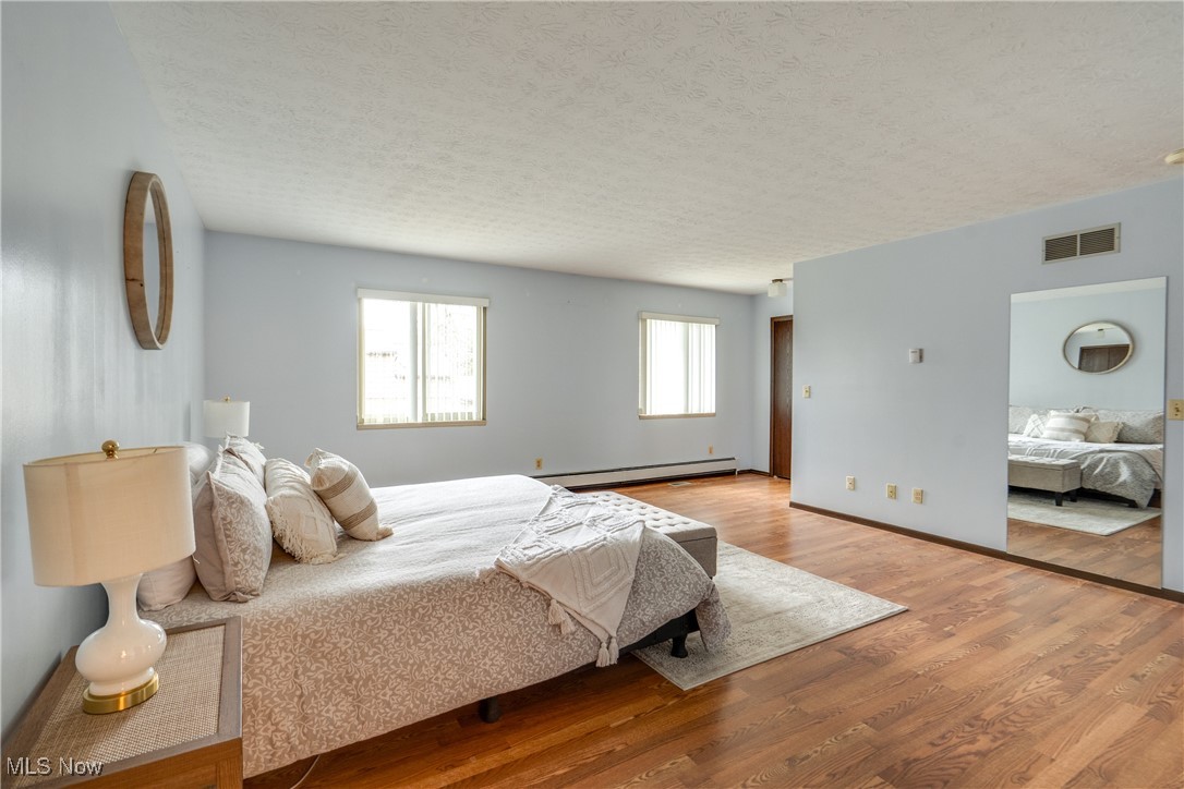 308 Guy's Run Road Akron, OH 44319 - Photo 27 of 44 Bedroom with a baseboard heating unit, a textured ceiling, wood finished floors, and visible vents