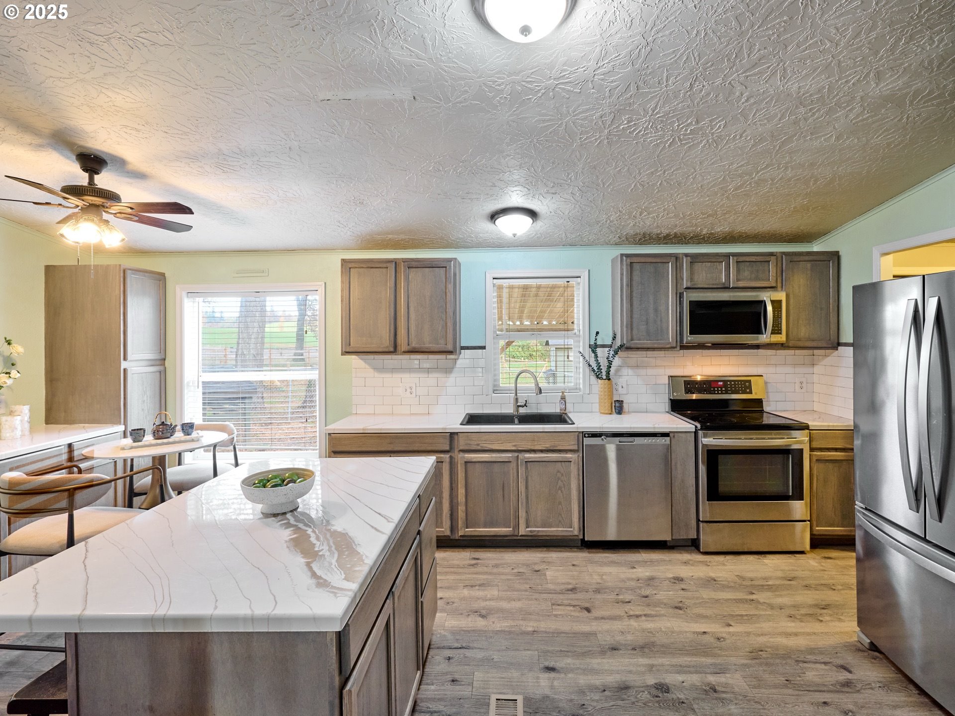 6288 Sherman Road Southeast Aumsville, OR 97325 - Photo 9 of 45 a large kitchen with granite countertop a stove top oven a sink dishwasher a dining table and chairs with wooden floor