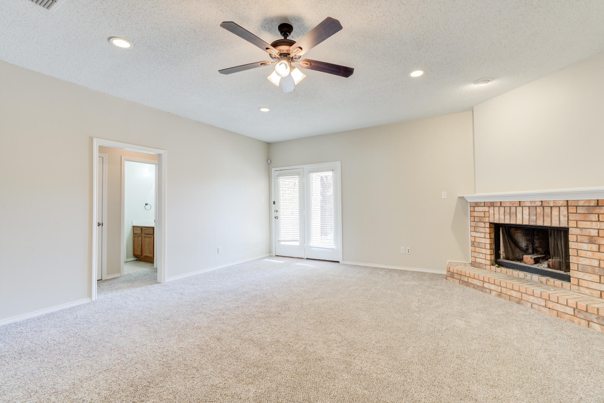 6713 85th Street Lubbock, TX 79424 - Photo 6 of 16 an empty room with fireplace and fan