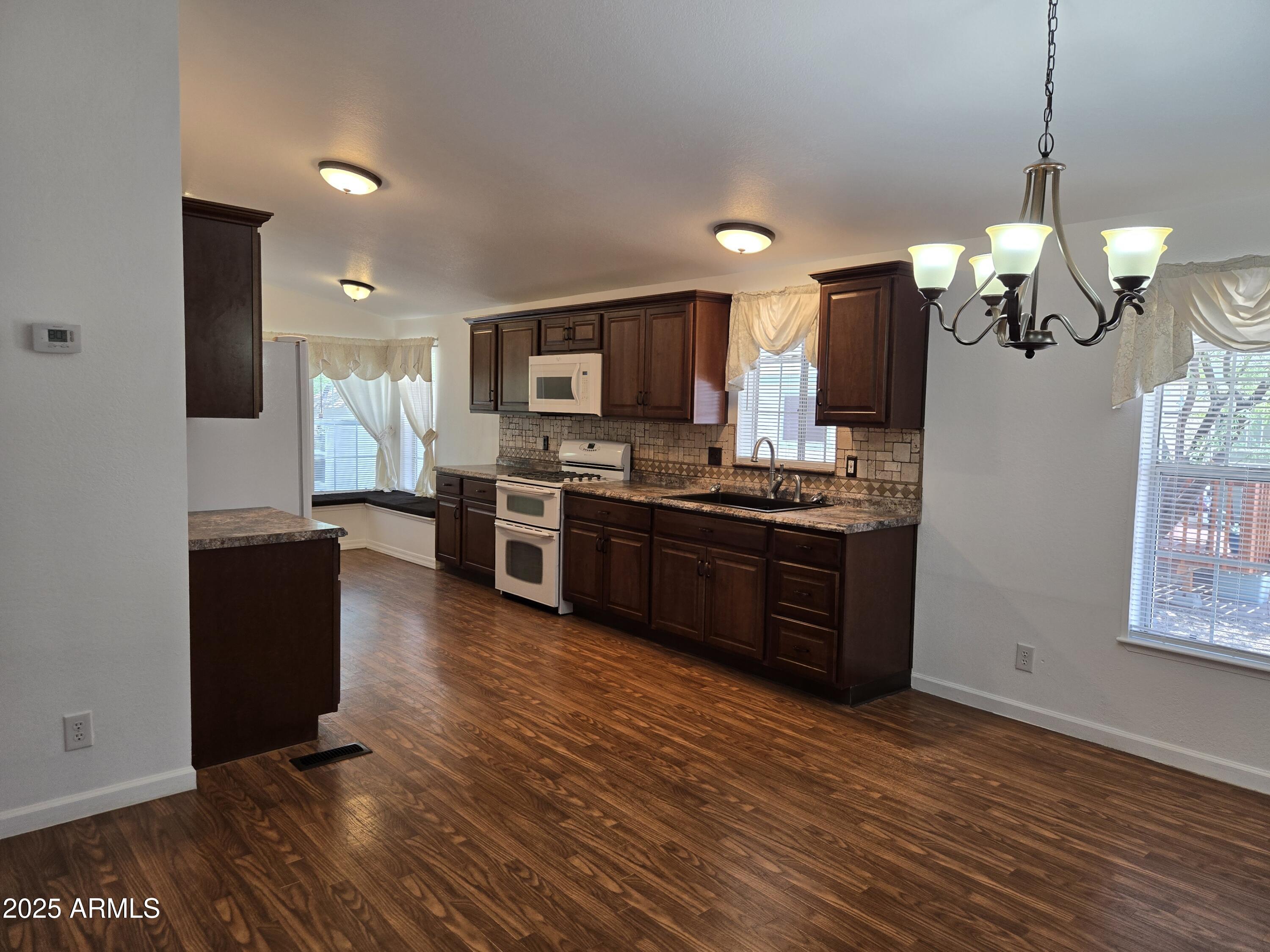 2000 South Apache Road, Unit 87 Buckeye, AZ 85326 - Photo 8 of 29 a kitchen with stainless steel appliances kitchen island granite countertop a stove a sink and a refrigerator