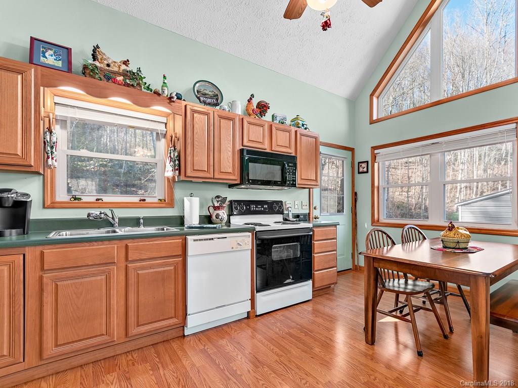 114 Turkey Creek Road Clyde, NC 28721 - Photo 5 of 12 a kitchen with granite countertop a stove top oven a sink dishwasher and white cabinets with wooden floor
