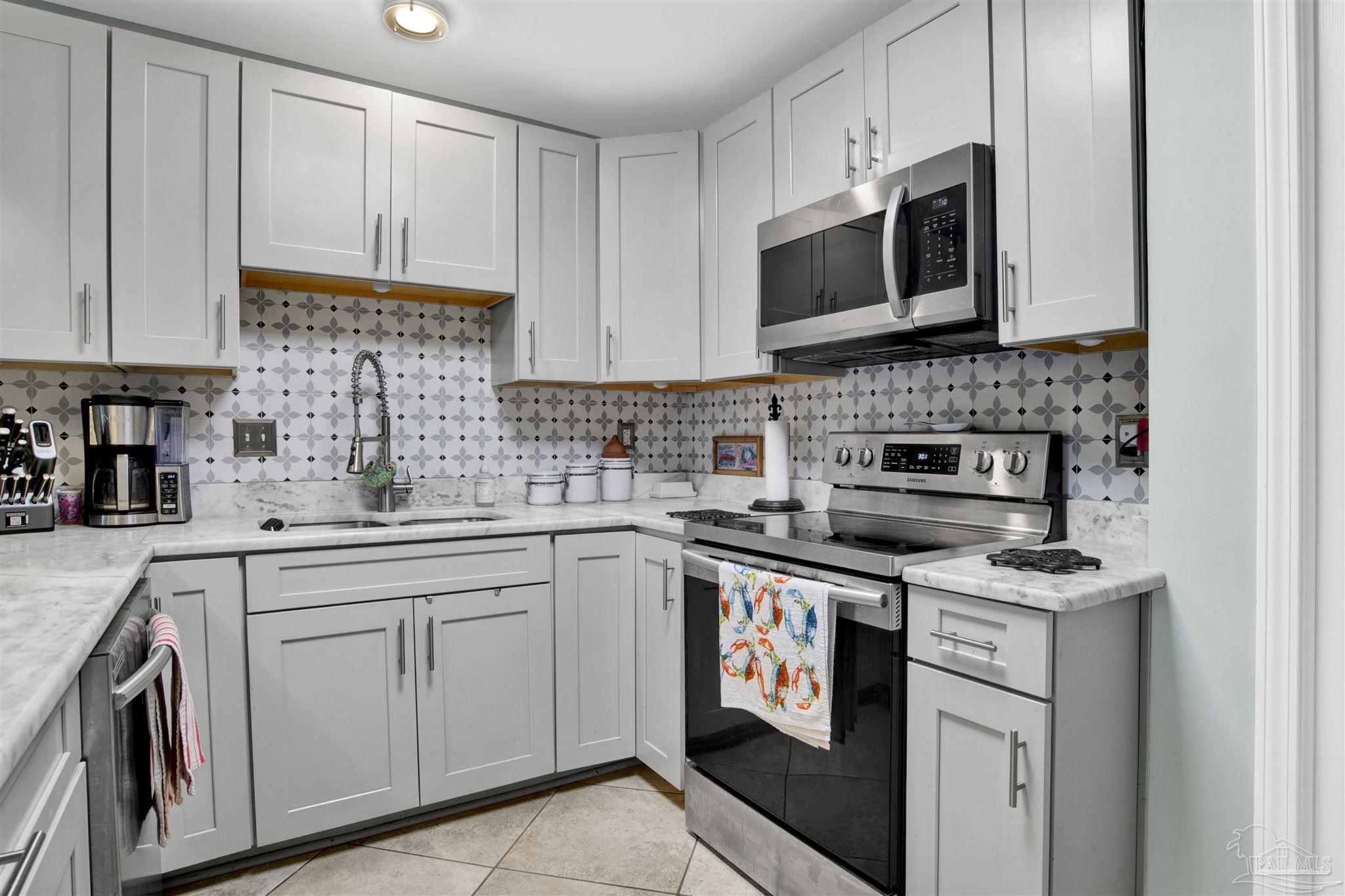 13351 Johnson Beach Road, Unit 203E Perdido Key, FL 32507 - Photo 12 of 55 a kitchen with stainless steel appliances granite countertop grey cabinets a stove a sink and a microwave